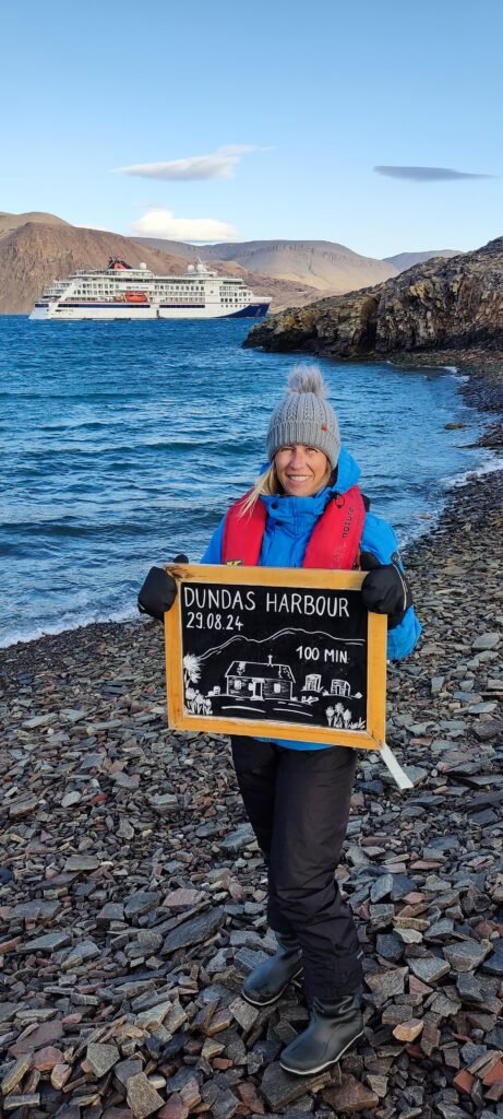 Vrouw in Dundas harbour Groenland met op de achtergrond het schip van Hanseatic Nature van Hapag-loyd cruises