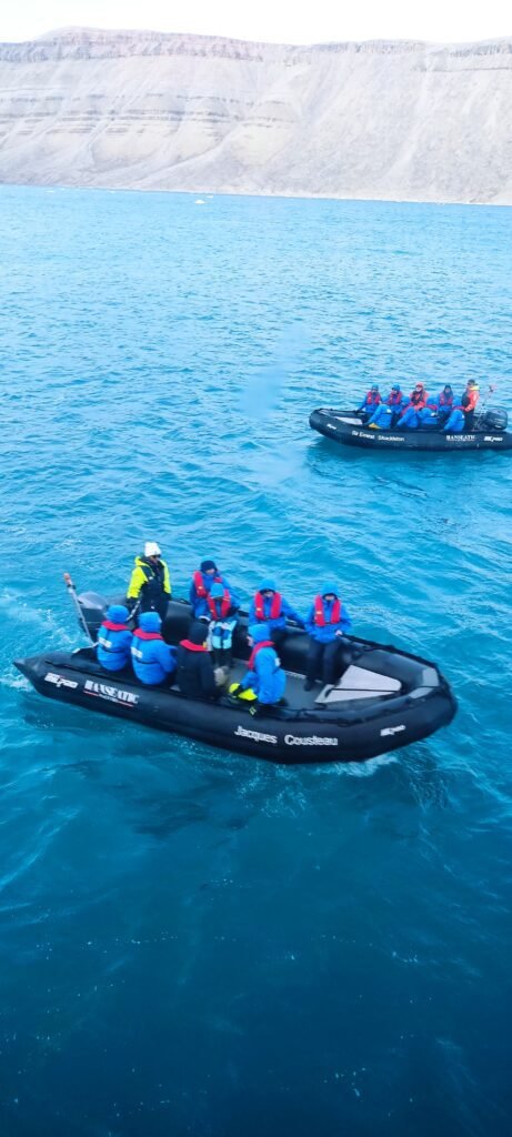 zodiacs in het water met mensen in met op de achtergrond hoge bergen in Groenland-cruise-Hapag-Lloyd